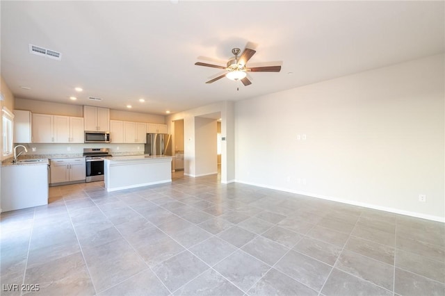 kitchen featuring visible vents, a sink, stainless steel appliances, light countertops, and open floor plan