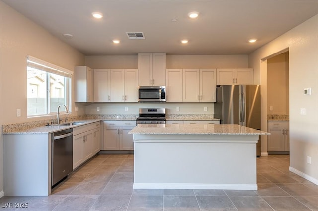 kitchen with light stone counters, visible vents, a sink, appliances with stainless steel finishes, and a center island