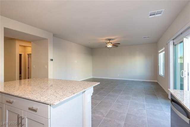 kitchen with visible vents, a ceiling fan, baseboards, light tile patterned floors, and light stone countertops