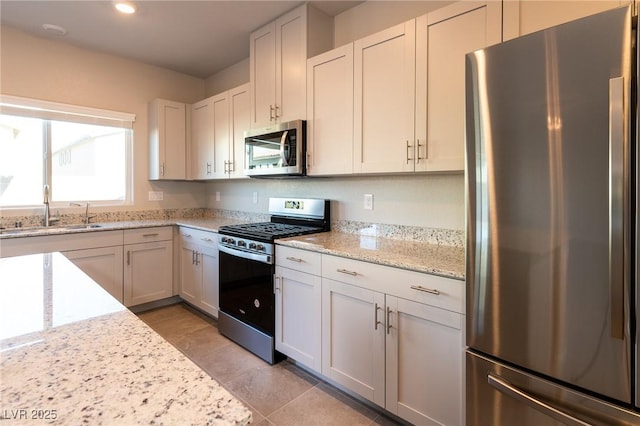 kitchen featuring a sink, recessed lighting, appliances with stainless steel finishes, white cabinets, and light stone countertops