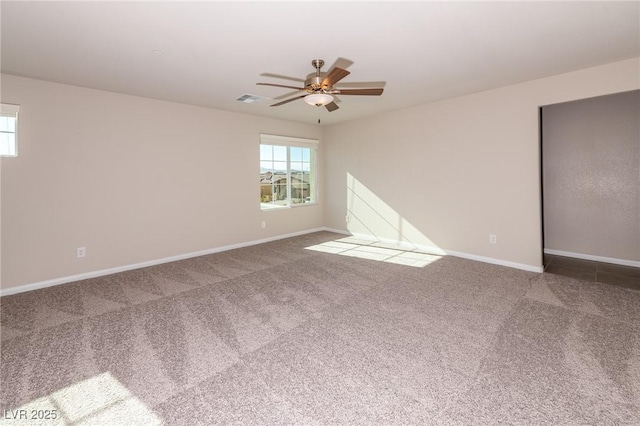 carpeted spare room with visible vents, baseboards, and a ceiling fan