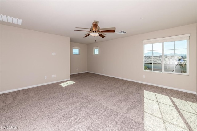 carpeted spare room with visible vents, ceiling fan, and baseboards