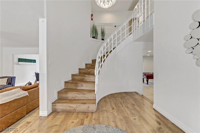 stairway with baseboards, a high ceiling, and wood finished floors