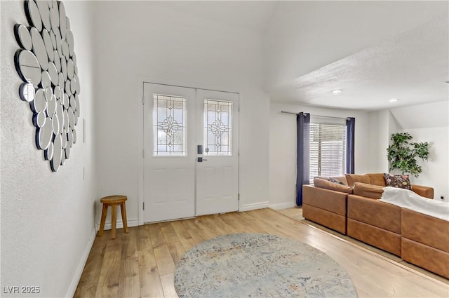 foyer featuring vaulted ceiling, baseboards, and light wood-type flooring