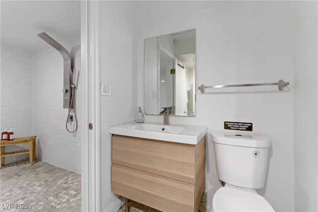 bathroom with tiled shower, toilet, and vanity