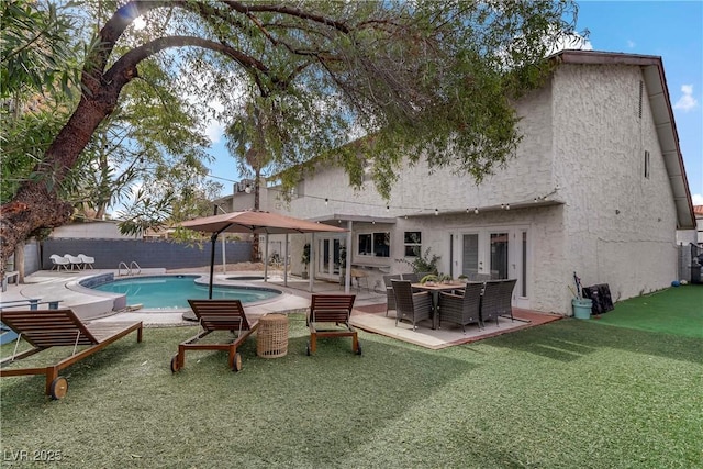 rear view of house with stucco siding, a fenced in pool, a fenced backyard, and french doors