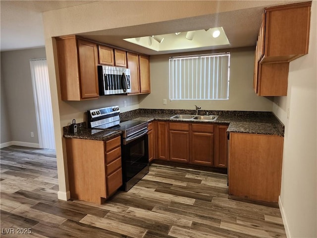 kitchen with a sink, dark wood-type flooring, brown cabinetry, and stainless steel appliances