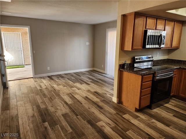 kitchen with baseboards, dark wood-style floors, brown cabinets, and stainless steel appliances