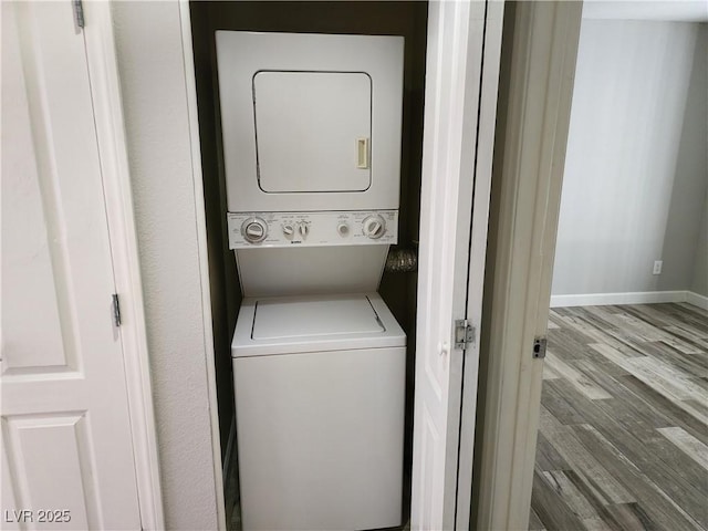 laundry room with laundry area, wood finished floors, baseboards, and stacked washing maching and dryer