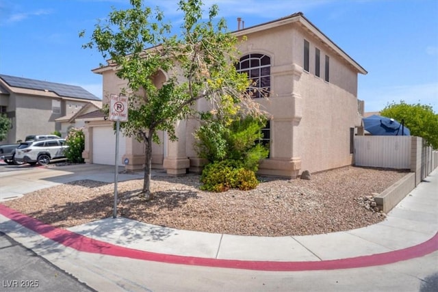 view of front facade with stucco siding, concrete driveway, a garage, and fence