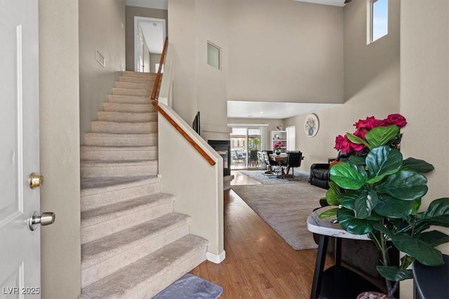 foyer with stairs, a high ceiling, wood finished floors, and baseboards