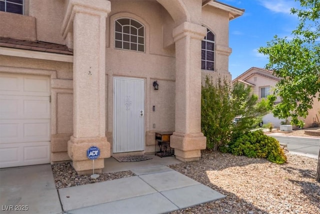 doorway to property featuring stucco siding and a garage