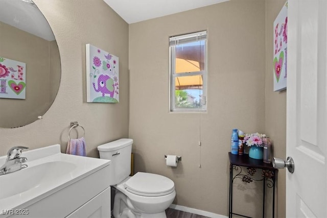 bathroom with baseboards, toilet, and vanity