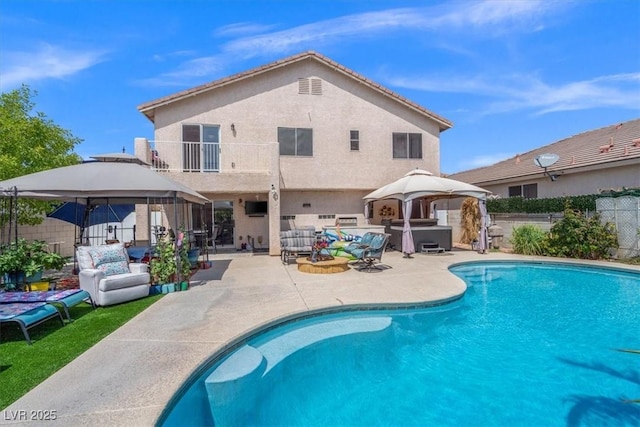 back of property with a balcony, an outdoor hangout area, fence, and a hot tub