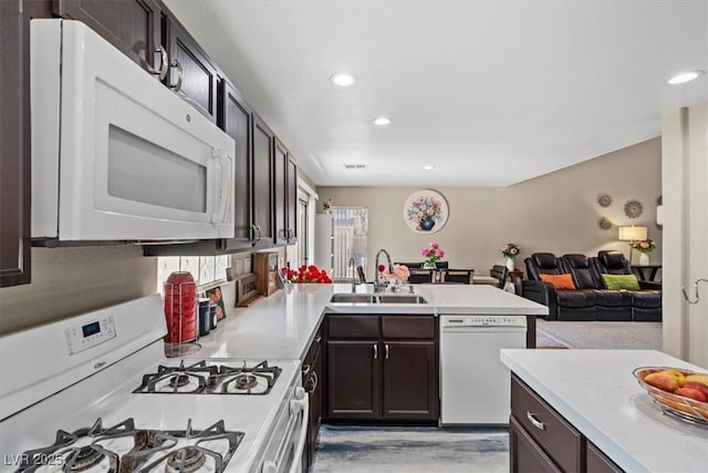 kitchen featuring a sink, white appliances, a peninsula, and light countertops