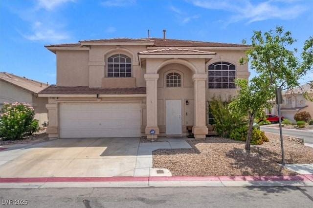 mediterranean / spanish home featuring stucco siding, concrete driveway, an attached garage, and a tiled roof