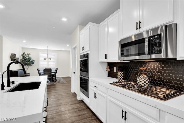 kitchen featuring a sink, stainless steel appliances, dark wood-style floors, and white cabinets