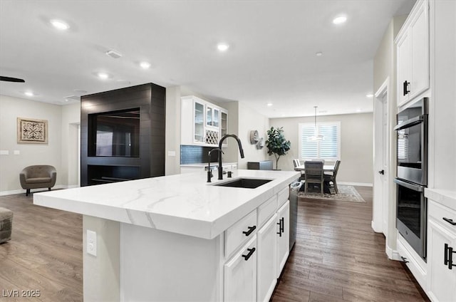 kitchen featuring a sink, an island with sink, recessed lighting, stainless steel appliances, and dark wood-style flooring