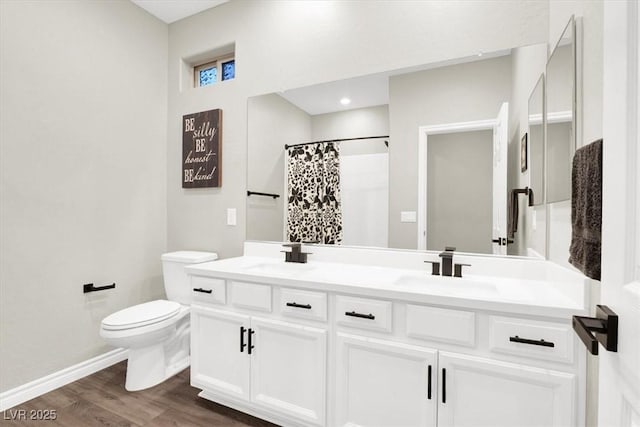 bathroom with toilet, wood finished floors, baseboards, and a sink