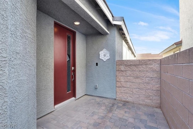 doorway to property with fence and stucco siding