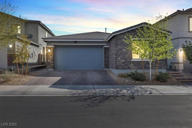 view of front of house featuring stone siding, driveway, and an attached garage