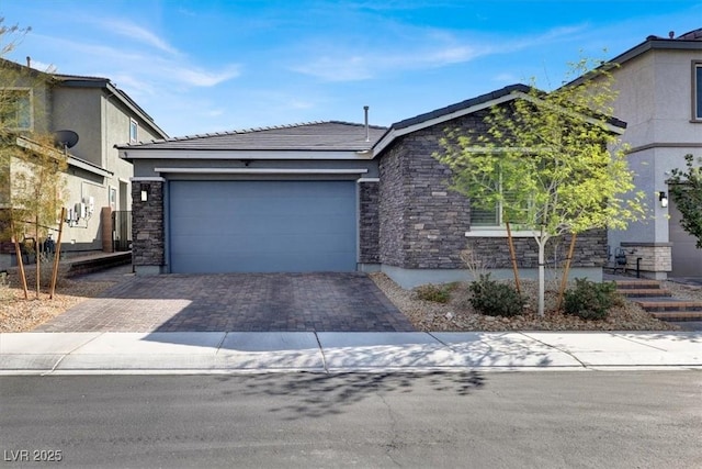 view of front of home with an attached garage, stucco siding, stone siding, a tile roof, and decorative driveway