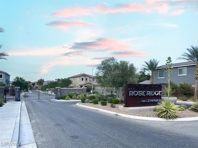 view of street with a gate, curbs, sidewalks, and a gated entry