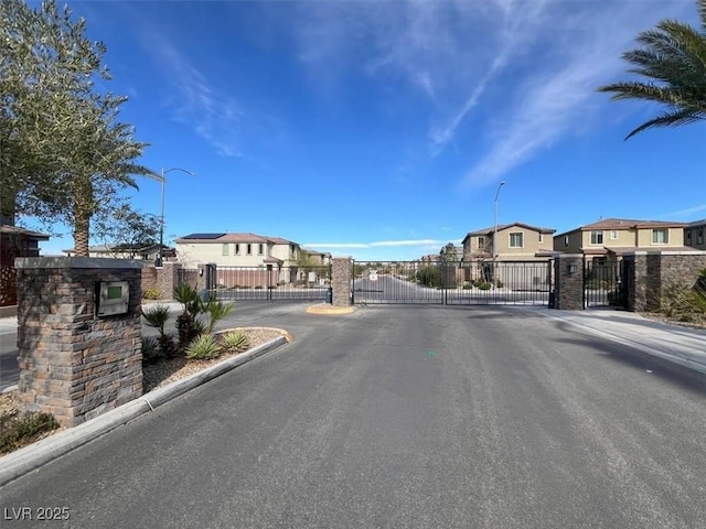 view of street with a gate, street lighting, a residential view, and a gated entry