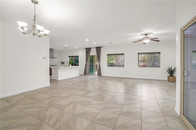 unfurnished living room featuring recessed lighting, baseboards, and ceiling fan with notable chandelier