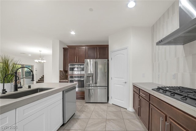 kitchen featuring a sink, wall chimney range hood, backsplash, appliances with stainless steel finishes, and light countertops