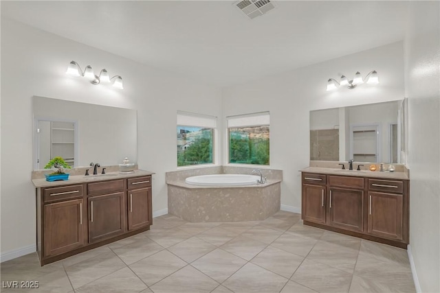 full bathroom with two vanities, a bath, visible vents, and a sink