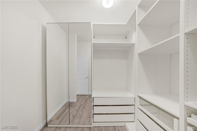 walk in closet with light wood-style floors