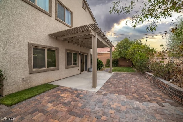 patio terrace at dusk featuring a fenced backyard and a pergola