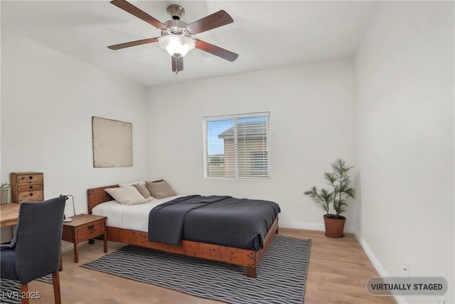 bedroom with light wood finished floors, a ceiling fan, and baseboards