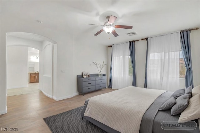 bedroom featuring light wood-style flooring, multiple windows, arched walkways, and visible vents