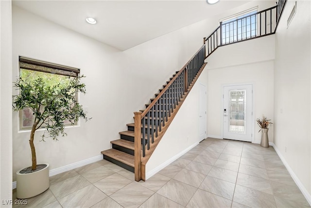 foyer featuring recessed lighting, a high ceiling, stairs, and baseboards