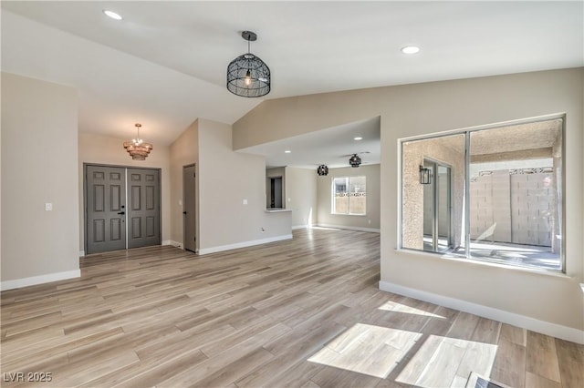 interior space featuring lofted ceiling, recessed lighting, baseboards, and light wood finished floors