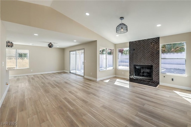 unfurnished living room featuring recessed lighting, light wood-style flooring, a tiled fireplace, and vaulted ceiling