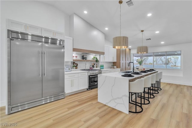 kitchen with light wood finished floors, visible vents, premium appliances, white cabinetry, and open shelves