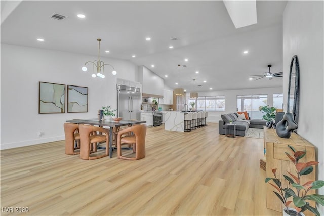 dining area with visible vents, lofted ceiling, light wood-style flooring, and ceiling fan with notable chandelier