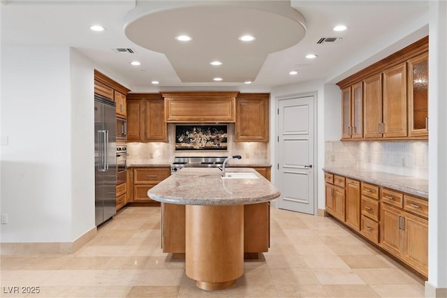 kitchen with visible vents, light stone counters, a sink, recessed lighting, and built in appliances