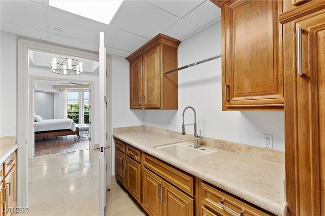 kitchen with light countertops, light tile patterned floors, brown cabinets, and a sink