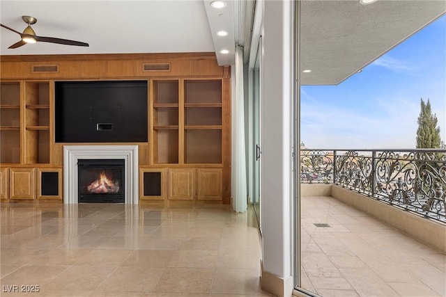 unfurnished living room with wooden walls, built in features, visible vents, and a lit fireplace