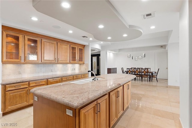 kitchen with visible vents, decorative backsplash, recessed lighting, brown cabinets, and a sink