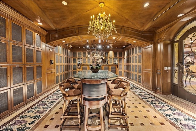 wine room featuring recessed lighting, arched walkways, wood walls, crown molding, and a chandelier