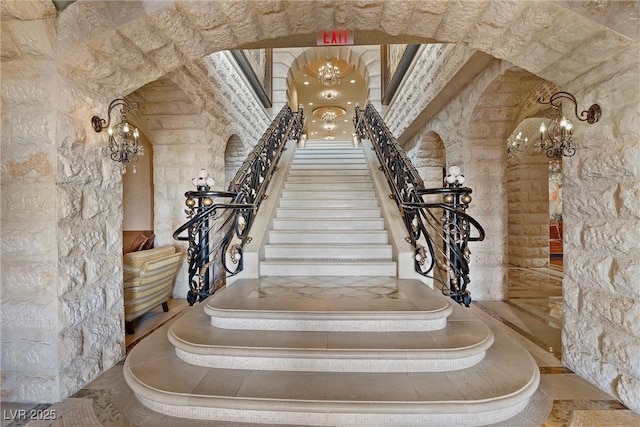 staircase with arched walkways and a notable chandelier