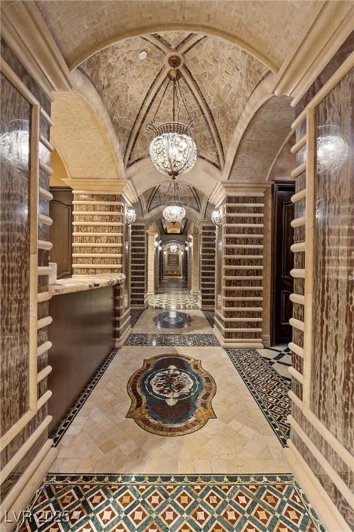 wine cellar with vaulted ceiling, brick ceiling, arched walkways, and a chandelier