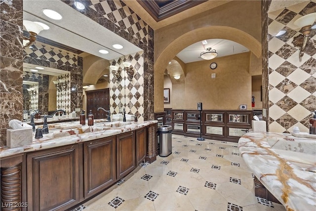 wine room with arched walkways, tile walls, ornamental molding, and light tile patterned flooring