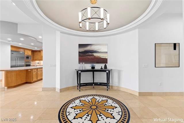 corridor featuring an inviting chandelier, baseboards, a tray ceiling, and ornamental molding