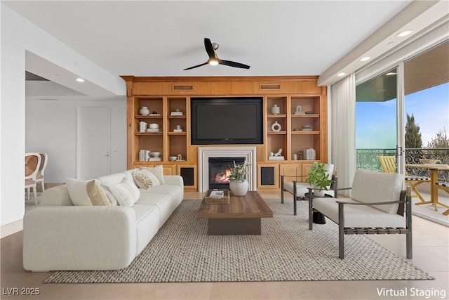 tiled living room featuring a glass covered fireplace, built in features, a ceiling fan, and recessed lighting